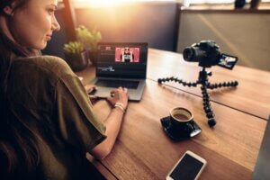 Young female vlogger looking at her camera while editing her vlo